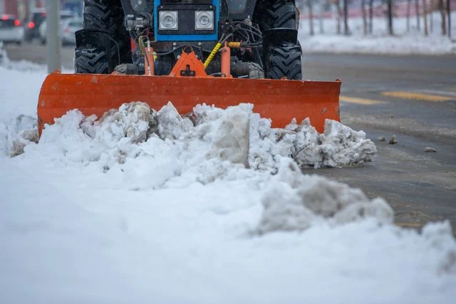 An ice-clearing vehicle plowing snow and ice from a city street.